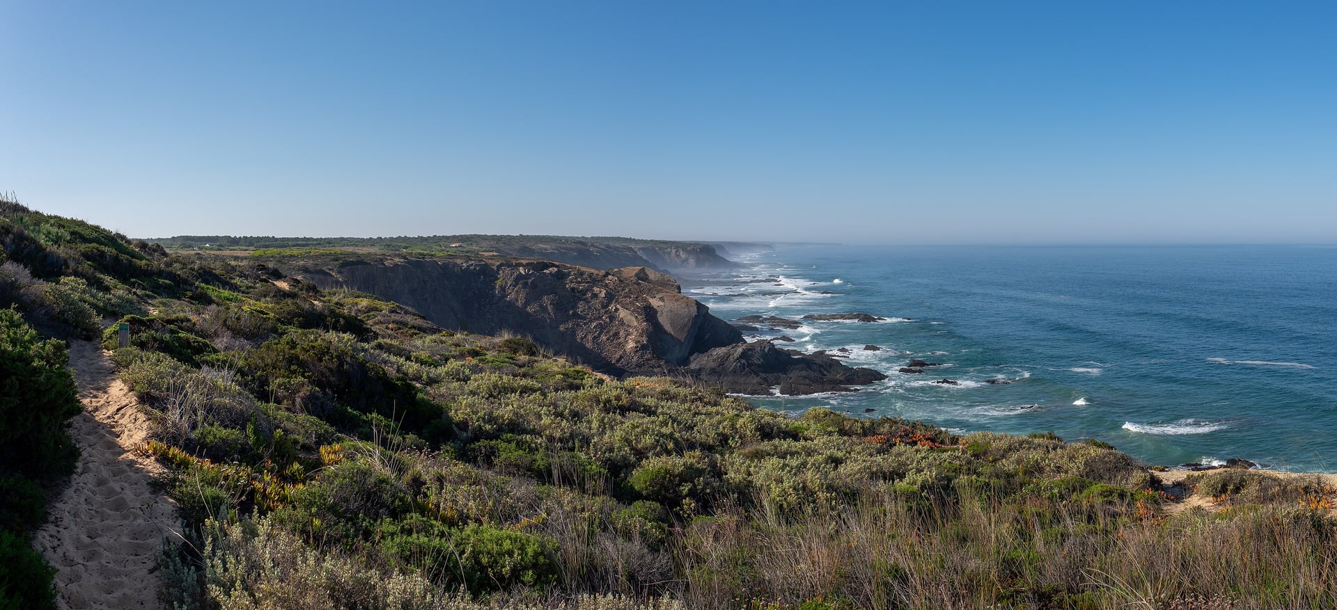 Sandy hiking path along the cliffs of the Fishermen's Trail near Odeceixe, with the Atlantic Ocean on the right