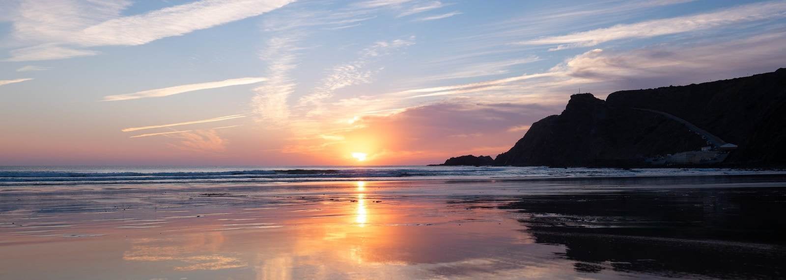Sunset over Praia da Arrifana, with the fortress silhouette on the headland