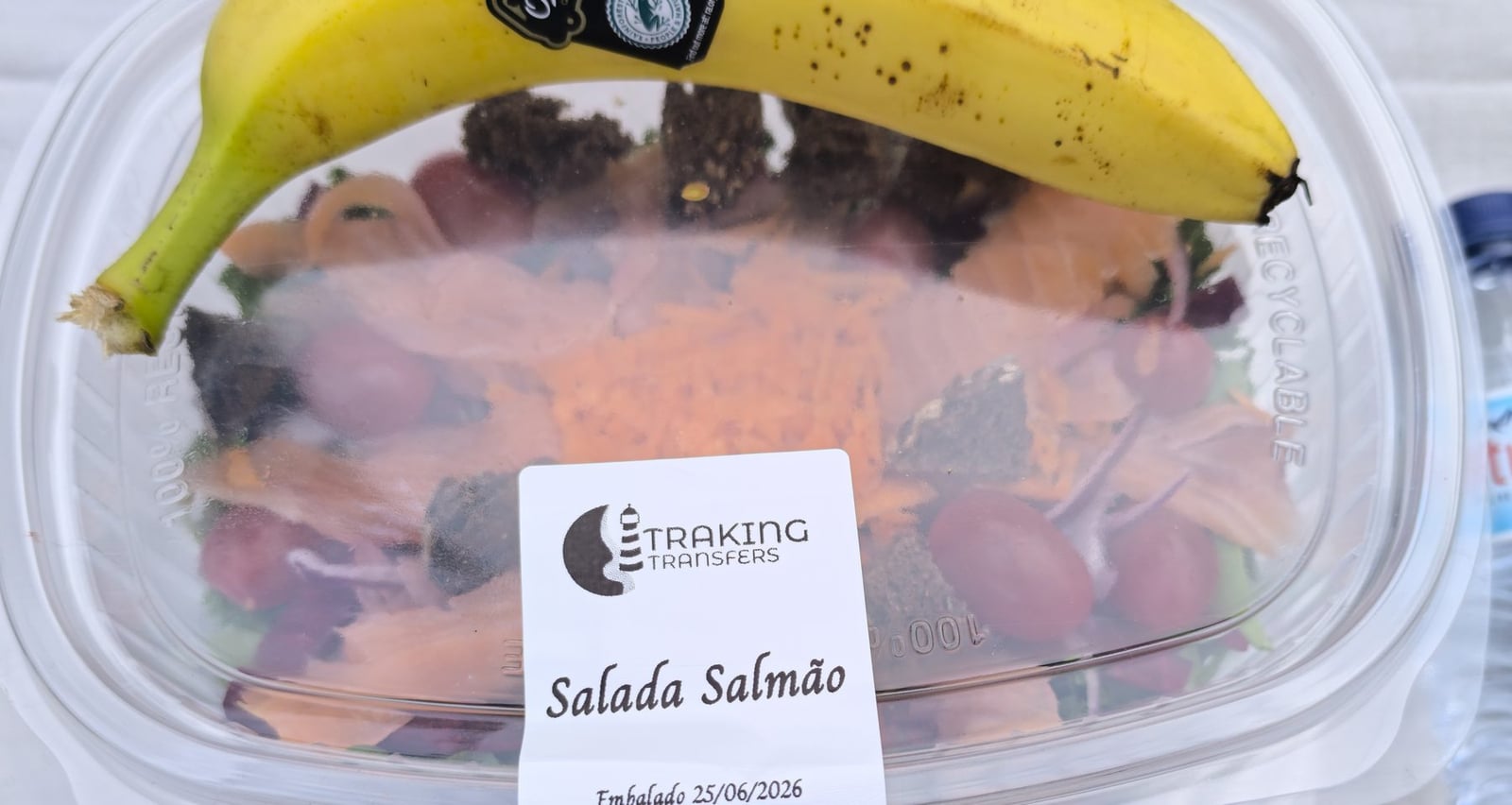 Traking Transfers Salmon Salad Pack label with banana on top and water bottle beside it